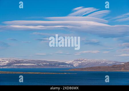 Nuages lenticulaires sur les paysages islandais, le fjord, l'île et les montagnes avec glacier et neige. Ciel bleu, mer bleu profond. Soleil. Vue panoramique Banque D'Images