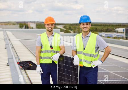 Portrait de travailleurs heureux installant des panneaux solaires sur le toit Banque D'Images