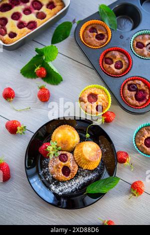Muffins au lait caillé sucré garnis de fraises, dans une assiette sur une table en bois. Banque D'Images