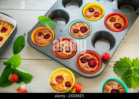 Muffins au lait caillé sucré garnis de fraises, dans une assiette sur une table en bois. Banque D'Images