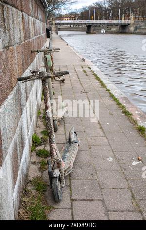 Scooters électriques récupérés, recouverts de boue et de petites coquilles, sur la rive ou la rivière aura à Turku, Finlande Banque D'Images