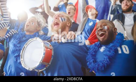 Sport Stadium Big Event : trois fans divers avec des visages peints acclamant, battant le tambour, riant, s'amusant, criant pour l'équipe de football à gagner. Les gens célèbrent l'attribution d'un but, la victoire de championnat Banque D'Images