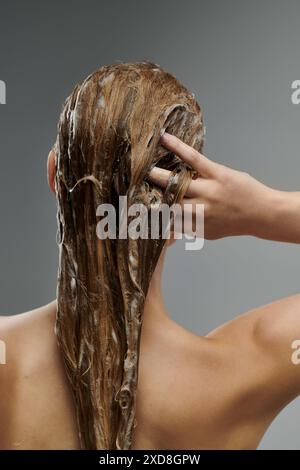 Une jeune belle femme démontre sa routine de soins capillaires, se lavant les cheveux. Banque D'Images