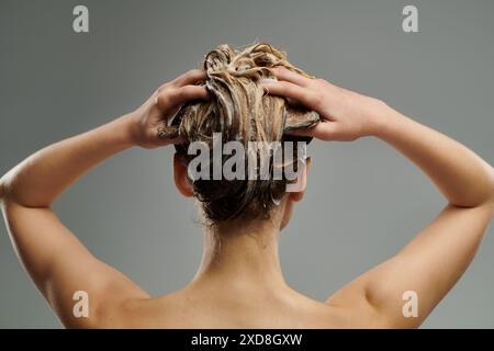 Une jeune femme démontre sa routine de soins capillaires avec les cheveux mouillés. Banque D'Images