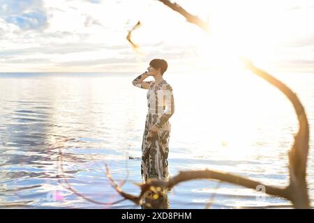 Une femme dans une longue robe à motifs debout dans l'eau peu profonde du Banque D'Images