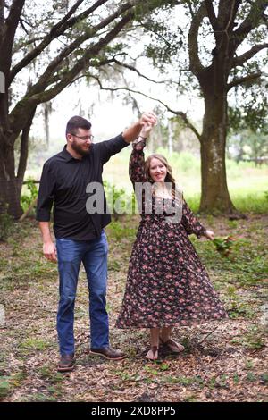 Couple enceinte dansant dans les bois, femme souriante tourbillonnant Banque D'Images