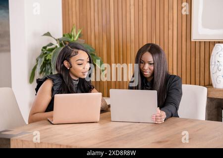 Des femmes d'affaires sérieuses travaillant à un grand bureau en bois sur leurs genoux Banque D'Images