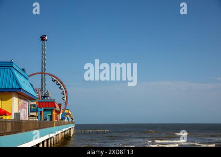 Parc d'attractions coloré sur une jetée au bord de l'océan sous un ciel bleu clair. Banque D'Images