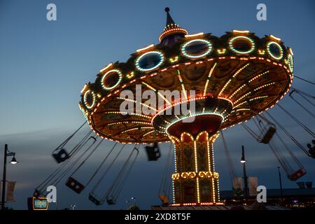 Balade éclairée en carrousel au crépuscule dans un parc d'attractions. Banque D'Images