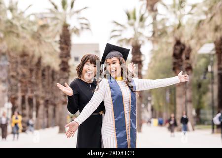 Mère excitée et fille diplômée le jour de la remise des diplômes avec Palm Banque D'Images