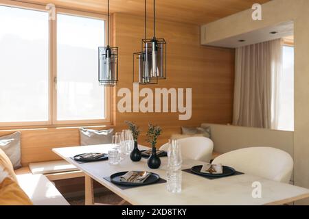 Table à manger moderne avec verrerie et vases dans une pièce confortable et ensoleillée Banque D'Images