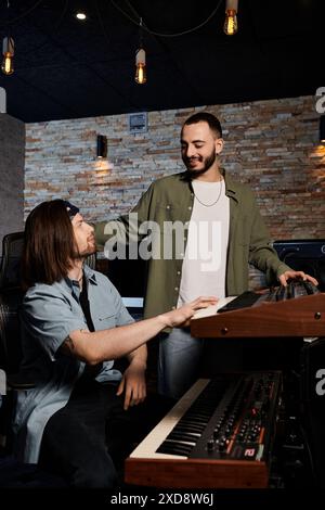 Deux musiciens talentueux se tiennent dans un studio d'enregistrement, collaborant sur la musique pour leur prochain projet de groupe. Banque D'Images