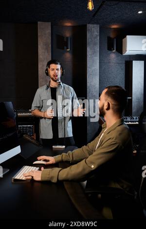 Deux hommes dans un studio d'enregistrement s'engagent dans une discussion animée lors d'une séance de répétition de groupe de musique. Banque D'Images