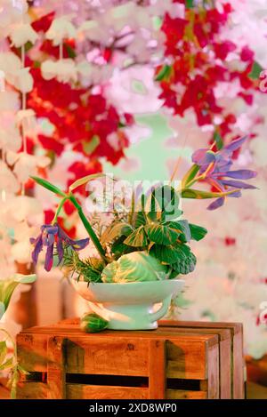 Arrangement floral avec des légumes et des fleurs sur une caisse en bois. Banque D'Images