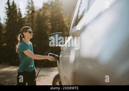 Femme charge la voiture électrique tout en conduisant dans le Colorado Banque D'Images