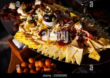 Élégante planche de charcuterie avec fromages artisanaux, charcuteries et olives Banque D'Images