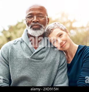 Couple mûr, portrait et détente en plein air pour la retraite, les vacances et le lien avec le soleil ou l'éruption. Mariage interracial, visage et personnes dans la nature Banque D'Images