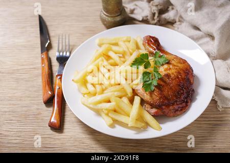 assiette de cuisse de poulet cuit au four avec des frites sur une table en bois Banque D'Images