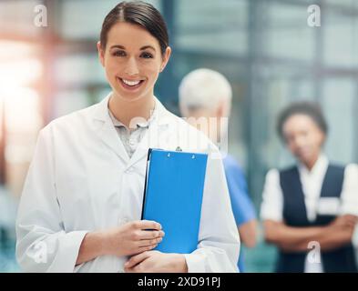 Femme, médecin et presse-papiers en portrait à l'hôpital avec sourire, travaillant dans les soins de santé et la médecine. Personne féminine, documents d'assurance maladie et Banque D'Images