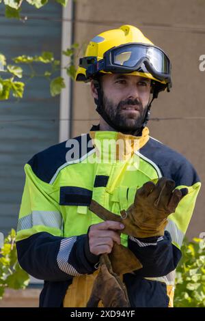 Pompier en uniforme et casque mettant des gants. Banque D'Images