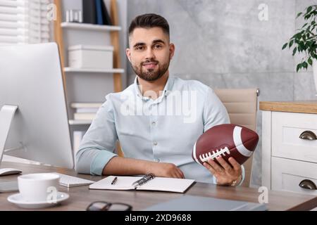 Jeune homme avec ballon de football américain à table dans le bureau Banque D'Images