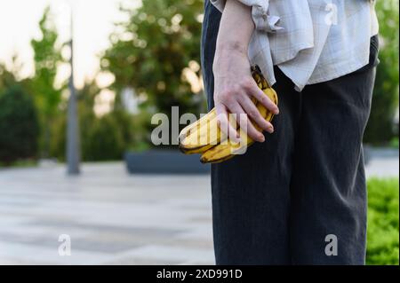 Gros plan de la main d'une femme tenant des bananes mûres. Concept Quick Snack. Banque D'Images