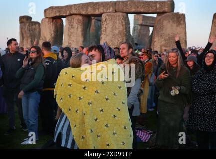 Salisbury, Angleterre, Royaume-Uni. 21 juin 2024. Un couple s'embrasse devant les pierres en attendant que le soleil se lève dans le cadre des célébrations du solstice d'été à Stonehenge. Stonehenge a été construit par les premiers Britanniques il y a environ 4000 ans pour s'aligner avec le soleil sur les solstices. Le solstice d'été marque la fin du printemps et le début de l'été et est le jour le plus long et la nuit la plus courte de l'hémisphère Nord. L'événement est célébré par des milliers de païens dans le monde entier avec du chant et de la danse. (Crédit image : © Martin Pope/ZUMA Press Wire) USAGE ÉDITORIAL SEULEMENT! Non destiné à UN USAGE commercial ! Banque D'Images