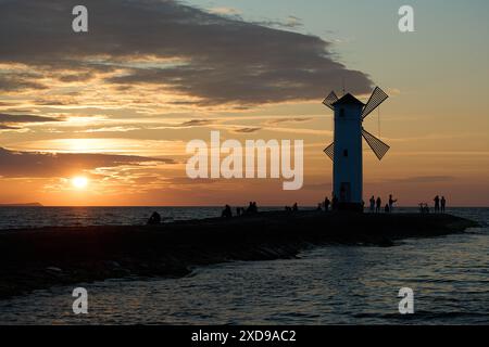 Moulin à vent à l'ancienne sur la jetée rocheuse sur la côte de l'île d'usedom le long de la mer baltique de Pologne avec beau coucher de soleil romantique et spectaculaire Banque D'Images