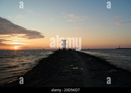 Moulin à vent à l'ancienne sur la jetée rocheuse sur la côte de l'île d'usedom le long de la mer baltique de Pologne avec beau coucher de soleil romantique et spectaculaire Banque D'Images