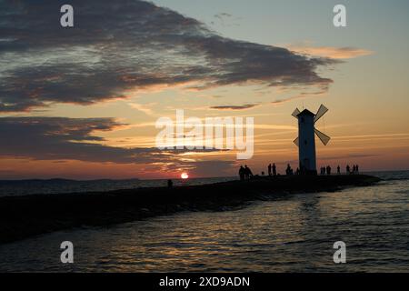 Moulin à vent à l'ancienne sur la jetée rocheuse sur la côte de l'île d'usedom le long de la mer baltique de Pologne avec beau coucher de soleil romantique et spectaculaire Banque D'Images