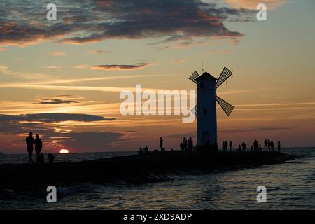 Moulin à vent à l'ancienne sur la jetée rocheuse sur la côte de l'île d'usedom le long de la mer baltique de Pologne avec beau coucher de soleil romantique et spectaculaire Banque D'Images