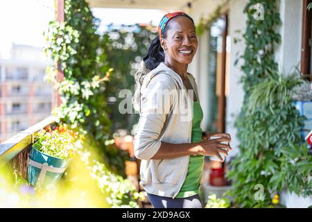 Portrait de femme souriante debout sur le balcon à la maison Banque D'Images