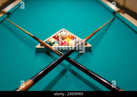 Accessoires de billard boules et queues croisées sur une table de billard Banque D'Images