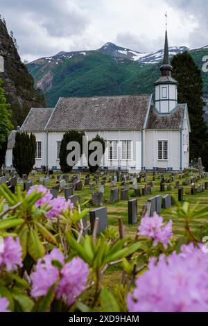 Une église blanche se dresse dans un cimetière entouré de fleurs roses, avec un fond de montagnes verdoyantes en Norvège. Vue sur le village Sylte ou Valldal Banque D'Images