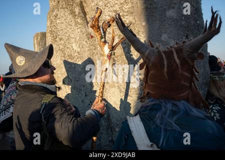 Les fêtards spirituels célèbrent le solstice d'été (mi-été et jour le plus long) parmi les anciennes pierres du néolithique tardif de Stonehenge, le 21 juin 2024, dans le Wiltshire, en Angleterre. Le solstice d'été est le jour le plus long de l'hémisphère nord et la nuit la plus courte de l'année, lorsque l'axe de la terre est incliné à son point le plus proche du soleil et les païens disent que l'ancien monument est un lieu sacré qui relie la Terre, la Lune, le Soleil et les saisons. Stonehenge a été construit en trois phases entre 3 000 av. J.-C. et 1 600 av. J.-C. Stonehenge appartient à English Heritage qui dit que 15 000 visiteurs ont été autorisés à entrer Banque D'Images