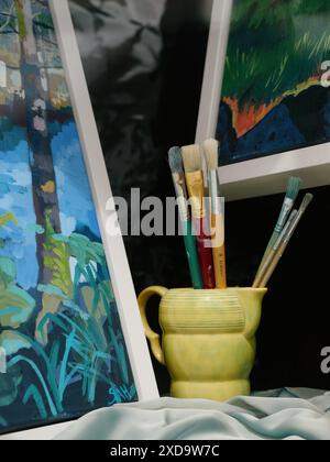 Une exposition artistique de peintures et de pinceaux dans une tasse jaune. Banque D'Images