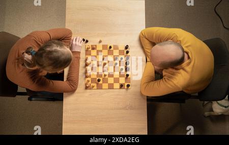 Deux hommes jouant aux échecs à la maison, vue aérienne, pensée stratégique, jeu de société en bois, cadre décontracté Banque D'Images