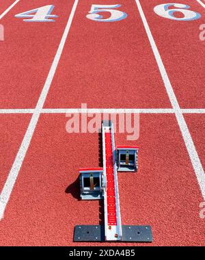 En regardant les coureurs qui partent des blocs dans la ligne cinq sur une piste rouge pour un sprinter. Banque D'Images