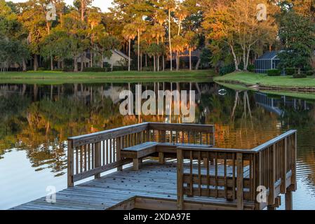 Les palmiers ensoleillés se reflètent dans un lac immobile tandis qu'une grande aigrette écume l'eau au coucher du soleil au Sawgrass Players Club à Ponte Vedra Beach, en Floride. (ÉTATS-UNIS) Banque D'Images