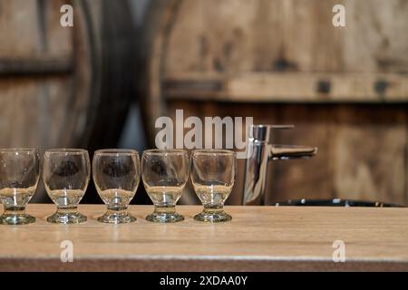 Verres vides à l'intérieur d'une cave à vin avec des tonneaux en arrière-plan en attente d'une visite de dégustation de vin à Cafayate, Salta, Argentine Banque D'Images