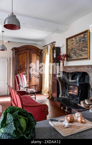 Armoire en bois et canapé avec poêle à bois dans un hôtel particulier en pierre rénové datant de 1770 à Saulieu, Bourgogne, France. Banque D'Images