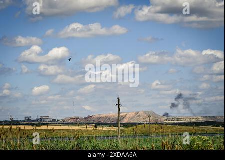 RÉGION DE DONETSK, UKRAINE - 13 JUIN 2024 - Un panache de fumée de coups se lève de derrière des bouts de butin sur les lignes de bataille dans la direction de Marinka, région de Donetsk, dans l'est de l'Ukraine. Banque D'Images