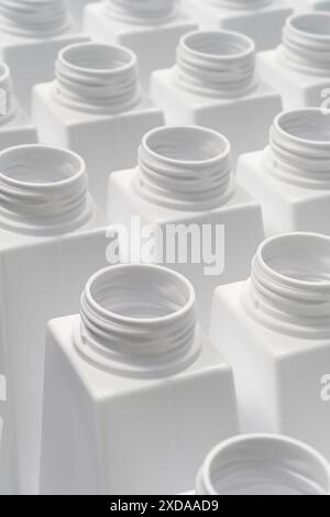 Grand groupe de bouteilles en plastique blanc vides prêtes à être remplies ou recyclées, ligne d'emballage ou de production, fond industriel abstrait Banque D'Images