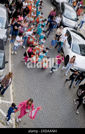 Enfants d'une école locale défilant dans une rue en costumes colorés avec des familles suivant la journée portugaise à São Vicente Banque D'Images