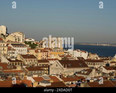 Panorama de la ville avec de nombreux toits et rivière au coucher du soleil avec un vieux bâtiment dans le centre, lisbonne, portugal Banque D'Images