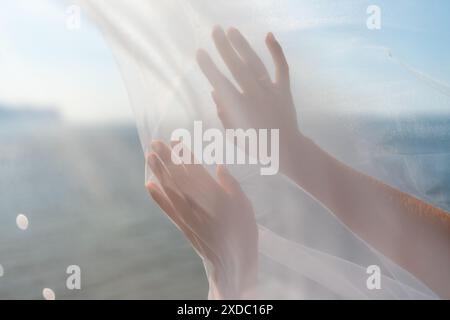 Les mains d'une femme sont montrées dans un voile blanc, avec le soleil qui brille dessus. Concept de paix et de sérénité, car les mains de la femme sont ouvertes et détendues. Banque D'Images