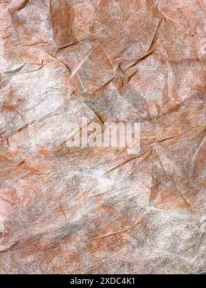 Cette image montre un gros plan de papier brun froissé et blanc. Le papier a été plié et froissé, créant une surface unique et texturée. Le Banque D'Images