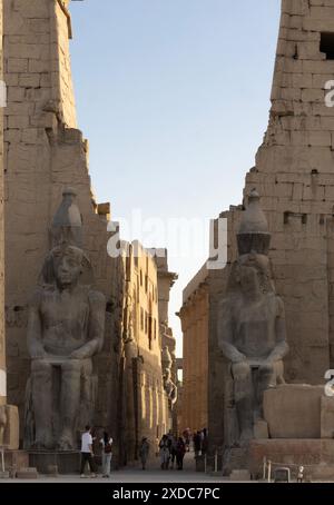 Deux statues colossales de Ramsès II gardent le pylône principal (passerelle) du temple de Louxor sur la rive est du Nil, en Égypte. Banque D'Images