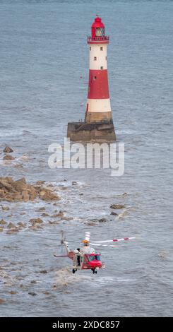 Sussex, Royaume-Uni. 21 juin 2024. HM Coastguard survole deux membres de l'équipage de la RNLI en mer à la recherche d'une personne disparue à côté du phare de Beachy Head avec le canot de sauvetage côtier de la RNLI à proximité. Beachy Head, Seven Sisters National Park, East Sussex, Royaume-Uni crédit : Reppans/Alamy Live News Banque D'Images