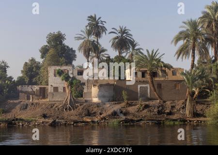 Un petit incendie brûle sur les rives du Nil juste après l’aube devant un village égyptien en brique de boue entre Esna et El-Kab.R. Banque D'Images